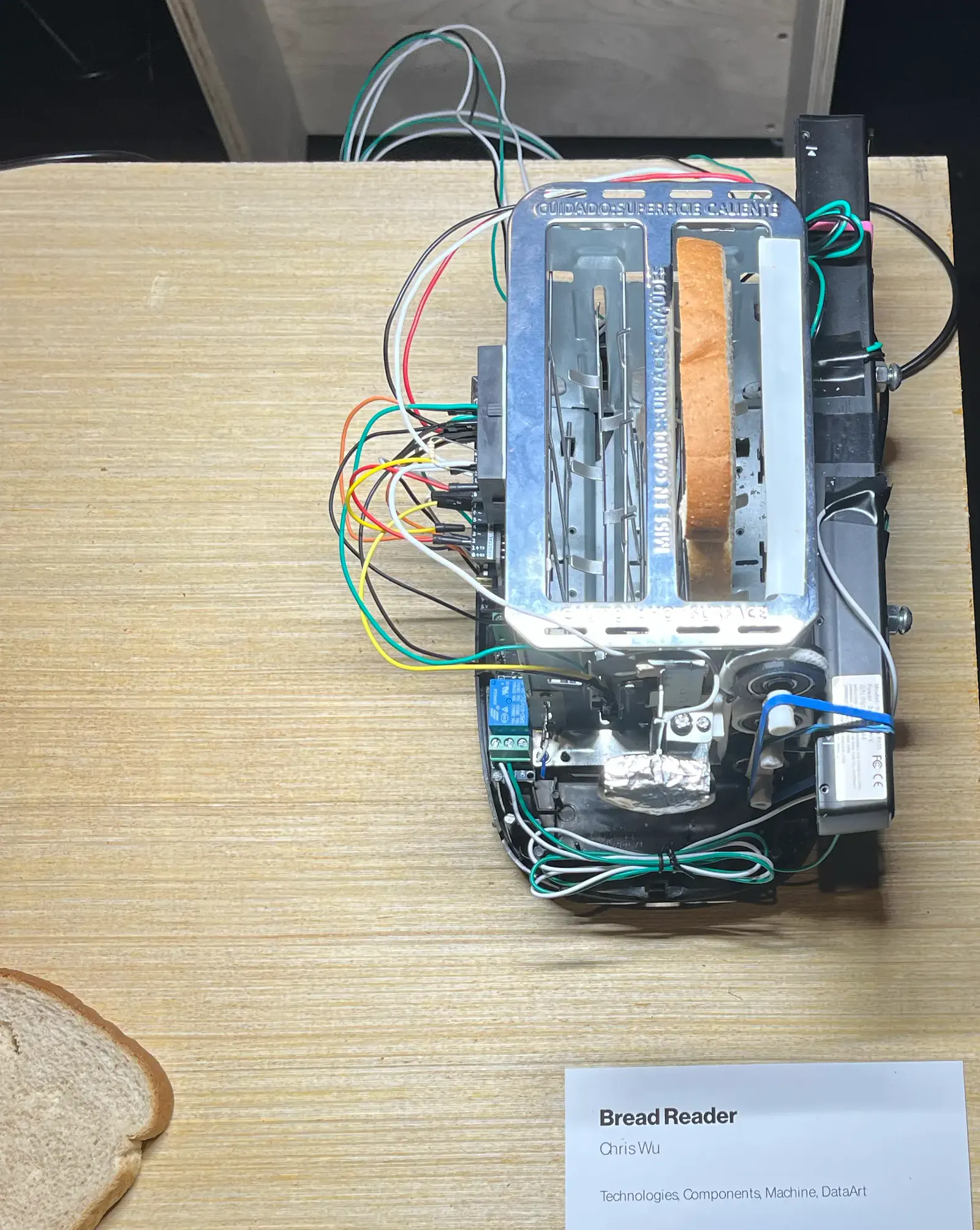 Bread Reader from above: a stripped toaster with a handheld scanner and wiring, a slice of bread beside it
